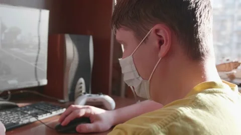 Guy plays on the computer in a protective mask and stays at home on self Video stock 130192792