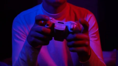 The guy plays the console. Holds a white gamepad in his hands Stock Footage 126504672