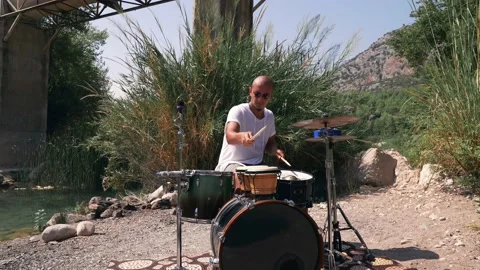 The guy plays drums coolly in the nature Expressive performance Medium Shot Stock Footage 139879084
