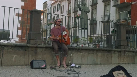 Guy plays guitar and sings on street of Funshal Stock Footage 88562573