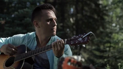 Guy plays the guitar on the lawn Stock Footage 79855357
