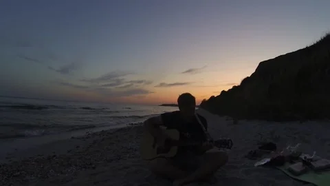 A guy plays guitar on the seashore against the sunset Stock Footage 196241672