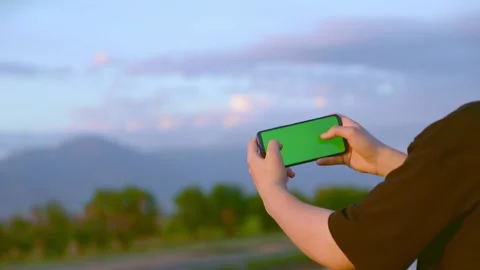 The guy plays in the phone with a green screen horizontally Stock-Footage 194393301