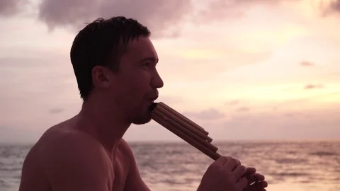 Guy plays a wind instrument by the sea 库存影片 119855678