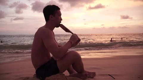 Guy plays a wind instrument by the sea Видео 119855692