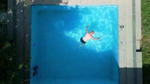 Guy in the pool on a bright sunny day, sporty guy in shorts Stock Footage 250874549