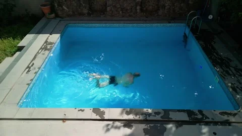 Guy in the pool on a bright sunny day, sporty guy in shorts Stock Footage 250885440