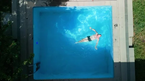 Guy in the pool on a bright sunny day, sporty guy in shorts Video stock 250918454