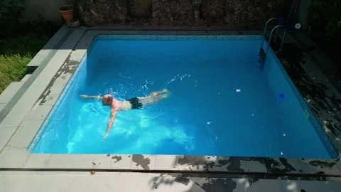 Guy in the pool on a bright sunny day, sporty guy in shorts Video stock 251019296