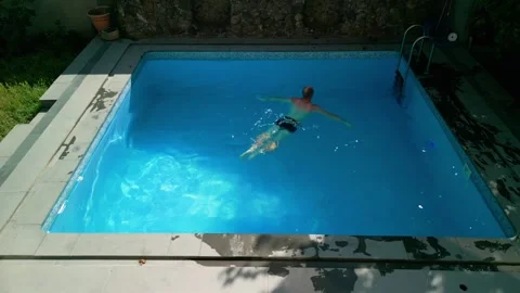 Guy in the pool on a bright sunny day, sporty guy in shorts Stock Footage 251024662