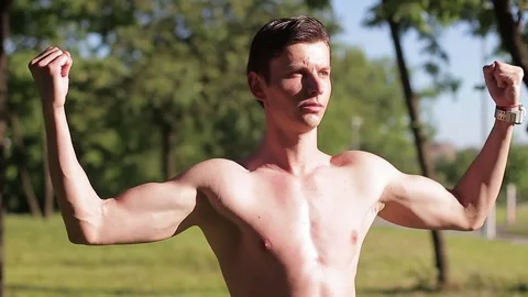 A guy posing without a T-shirt in the park. 스톡 동영상 76255513