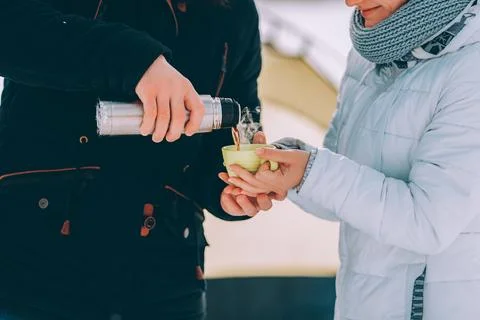 Guy pour hot coffee to his girlfriend in green cup. winter hike theme Stock Photos