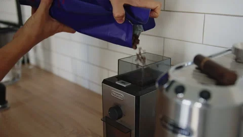 A guy pours coffee beans into a coffee grinder Stock Footage 306999540