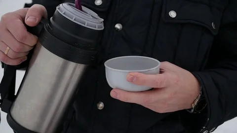 Guy pours hot tea from a thermos outdoors. Winter time 스톡 동영상 70076528