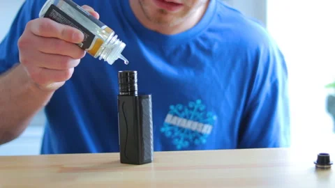 The guy pours liquid into the electronic cigarette Stock Footage 91358067