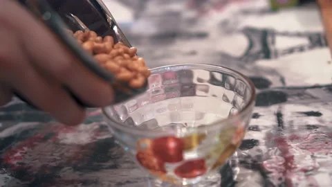 The guy pours nuts from one cup into another on the table. Close-up shooting Stock Footage 197490502