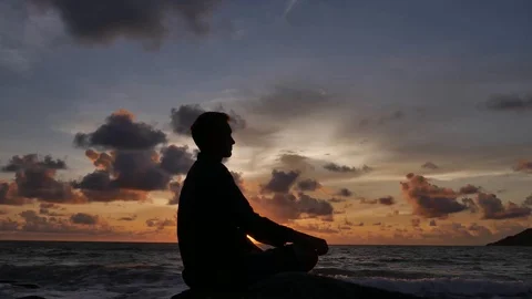 Guy practices meditation at sunset on the background of the sea time lapse Stock Footage 121299405