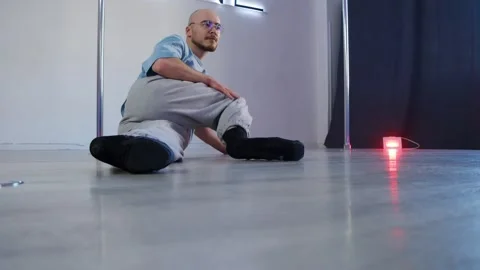 A guy is practicing high-heel pool dance moves in front of the mirror in a dance Stock Footage 305325410