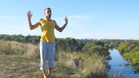 Guy practicing yoga moves and positions outdoors. Young man standing at yoga Stock Photos