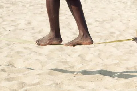 Guy practising slack line on the beach. Slacklining is a practice in balance  Stockfoto's