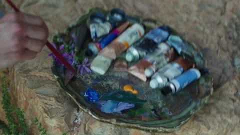 A guy prepares blue oil paint on the palette with a brush Stock Footage 141960959