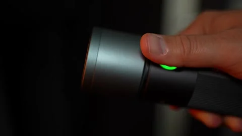 The guy presses the button on the flashlight and switches colors Stock Footage 325642044