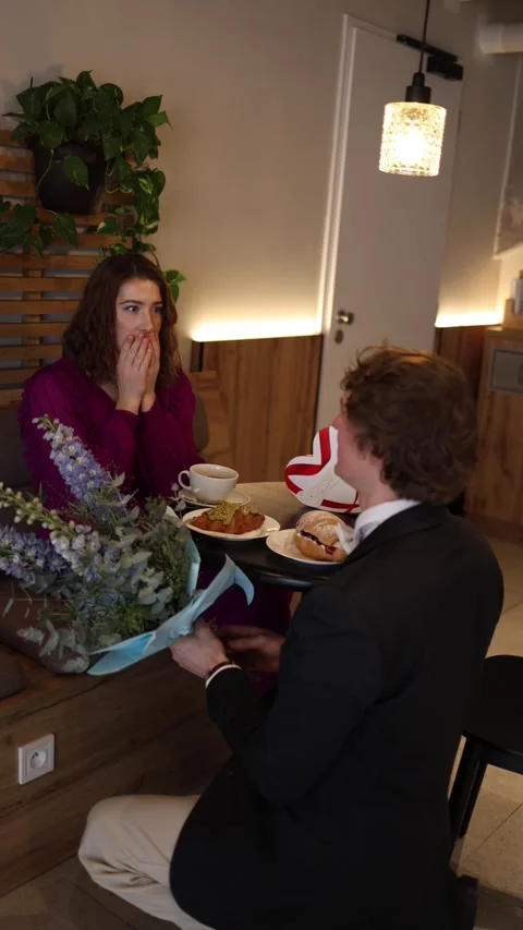 Guy proposes with flowers in cafe Stock Footage 328301279