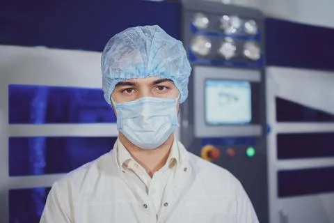 Guy in protective mask cap and robe near modern equipment Stock Photos