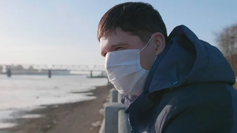 Guy in a protective mask stays on the riverfront. Prevention and protection of Vidéo 128069407