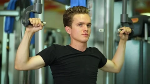 Guy pulling down handle with weight on fitness machine Stock Footage 64473975