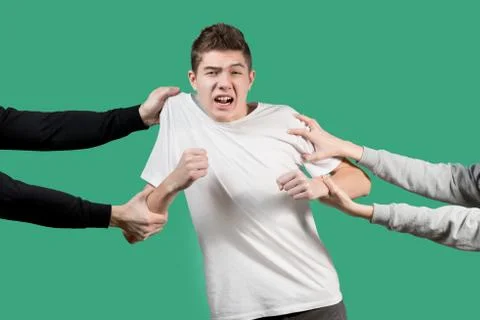 The guy is pulling by hands in different directions, the teenager is shocked  Stock Photos