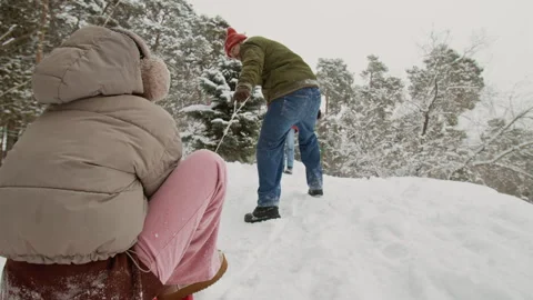 Guy Pulling Sled with Young Woman Uphill while Friends Enjoying Winter Activity Stock Footage 333260632