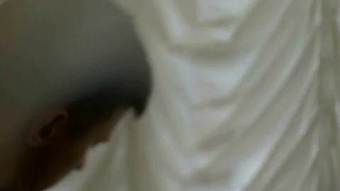 Guy pulls back the curtain and looks out the window close up Stock Footage 81397849