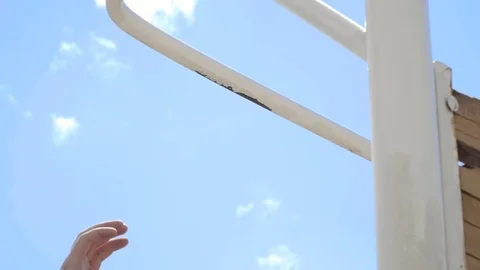 The guy pulls up on the bar. Workout outdoors. Blue sky on blackground. Slow Stock Footage 77718446