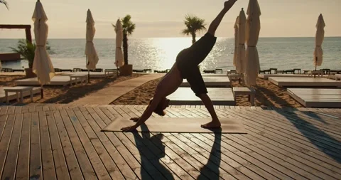 The guy pulls his legs up while doing yoga. Exercises to keep the body and mind Stock Footage 249310602