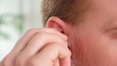 Guy pulls out case and inserts wireless headphones into ears. Young man showing Stock Footage 239447769