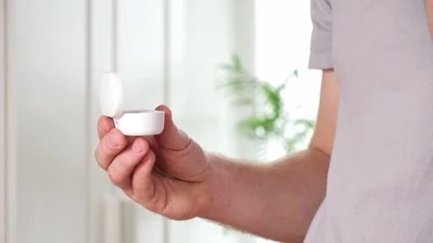 Guy pulls out case and inserts wireless headphones into ears. Young man showing Stock Footage 239448186