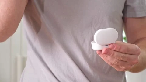 Guy pulls out case and inserts wireless headphones into ears. Young man showing Stock Footage 239448250