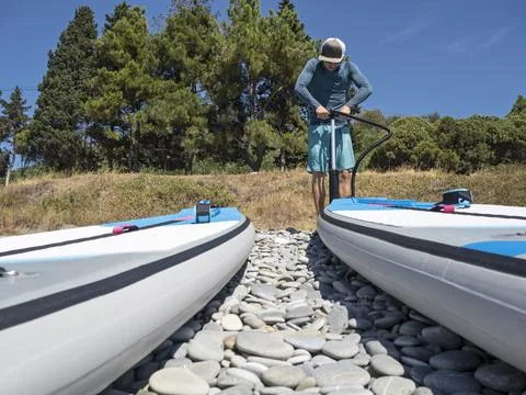Guy pumping up SUP 스톡 사진