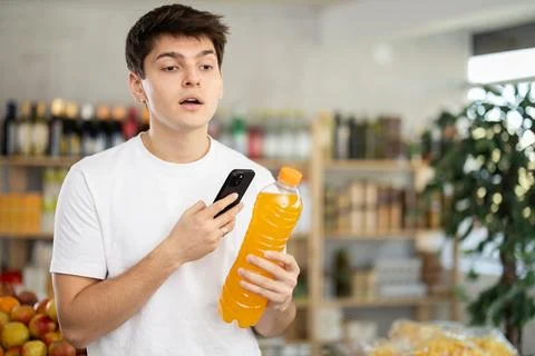 Guy purchaser scanning QR code or barcode bottle of water in supermarket Photos