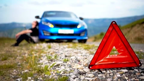 The guy put up an emergency stop sign and sits near the broken car Stock Footage 135404788