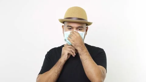 Guy put on hat in casual clothes wearing a face mask on isolated white backgroun Stock Footage 144651216