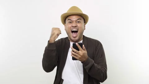  Guy put on hat in casual clothes look to smartphone posing doing winner gesture Stock Footage 144651402