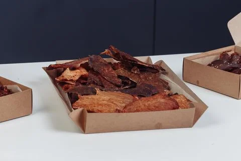 A guy puts dried meat in paper boxes in black gloves Stock Photos