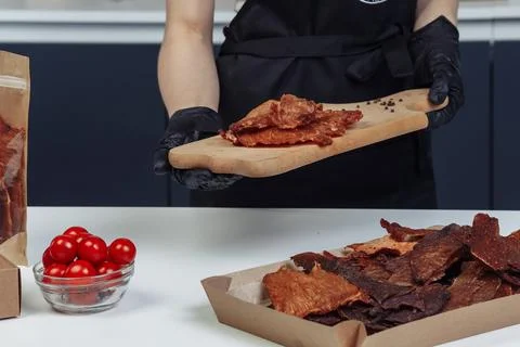 A guy puts dried meat in paper boxes in black gloves Stock Photos