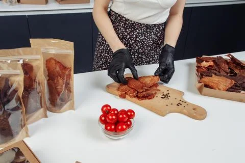 A guy puts dried meat in paper boxes in black gloves Stock Photos
