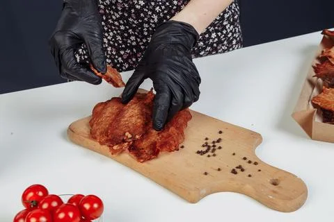 A guy puts dried meat in paper boxes in black gloves Stock Photos