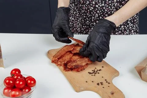 A guy puts dried meat in paper boxes in black gloves Stock Photos