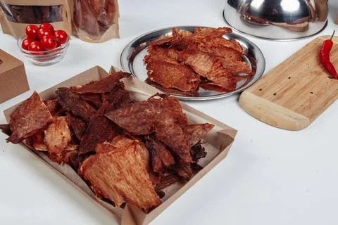 A guy puts dried meat in paper boxes in black gloves Stock Photos