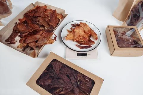 A guy puts dried meat in paper boxes in black gloves Stock Photos